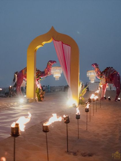 The entrance to the desert Mehendi was marked by a torch-lit path and a grand yellow arch flanked by decorated camel figures. This created a magical and dramatic welcome for guests as dusk settled.