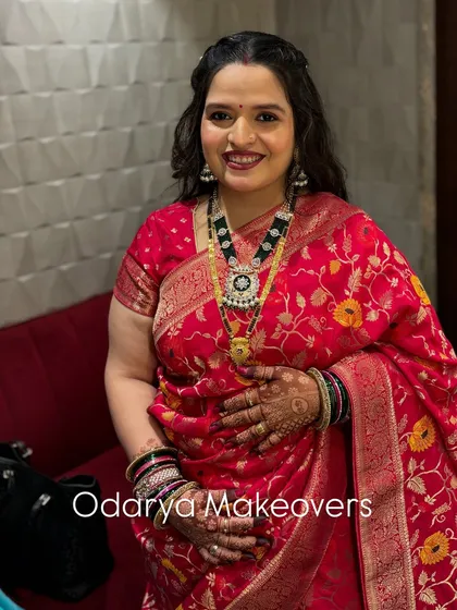 A full-length view of the naming ceremony look. The red Banarasi saree is beautifully draped to complement her glowing makeup.