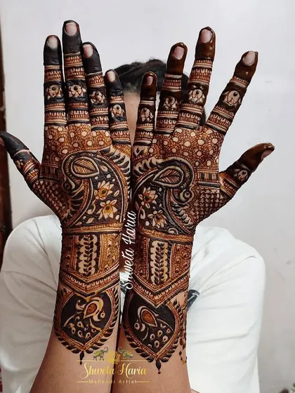 A stunning back-hand mehendi design with intricate details. The pattern features beautiful paisley and peacock motifs, with a bold meenakari effect that makes the design pop.