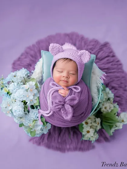This overhead shot shows a newborn wrapped in purple with a cute bear hat. I love using different angles to capture unique perspectives during a session.