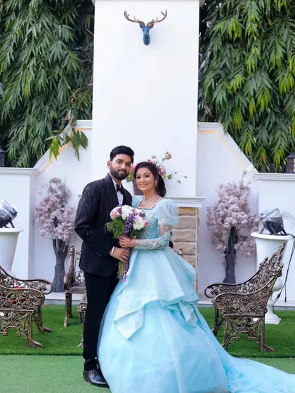A fairytale moment brought to life. The bride's beautiful blue ball gown and the groom's classic tuxedo create a picture-perfect scene against a whimsical, decorated backdrop.