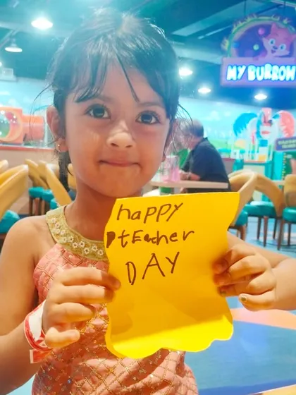 A young girl holds up a sweet handmade note for Teacher's Day. I encourage kids to express their gratitude through simple, heartfelt crafts during our special event days.