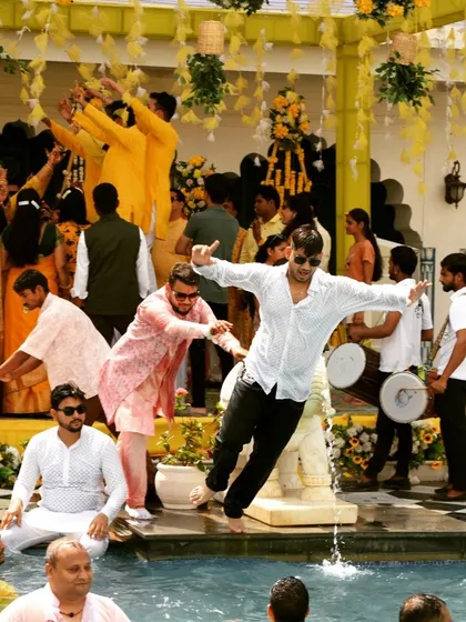 A candid shot of a guest joyfully jumping into the pool during a lively Haldi pool party.