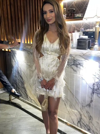 A perfect party dress for a cocktail night or bachelorette party. This custom ivory short dress features sheer sleeves with intricate embroidery using self-colored cutdana and salis, finished with dramatic feather detailing on the cuffs and hem.