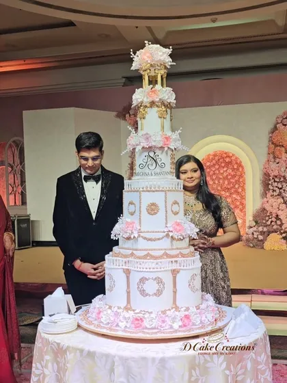A beautiful portrait of the engaged couple standing proudly beside their towering, custom-designed cake. The cake's design complements the luxurious and romantic atmosphere of the event.
