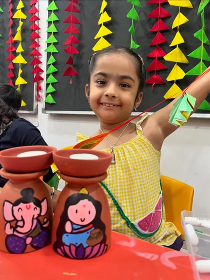 A joyful student showing off her beautifully painted Lakshmi-Ganesha tea-light holders.