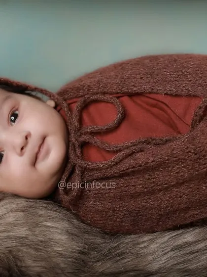 A close up of a swaddled two-month-old baby looking calmly at the camera. These shots focus on their developing features and expressive eyes.