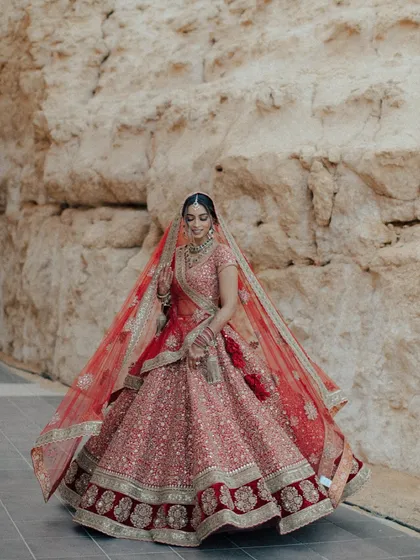A full-length shot of the bride in her magnificent red lehenga, a vision of grace and beauty.