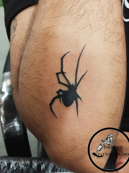A close-up of a black spider tattoo, showing the clean lines and solid fill. A striking and powerful piece.