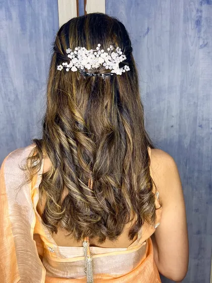 Soft curls are a versatile choice that works for any occasion. Here, they are styled in a simple half-updo with a beautiful accessory.