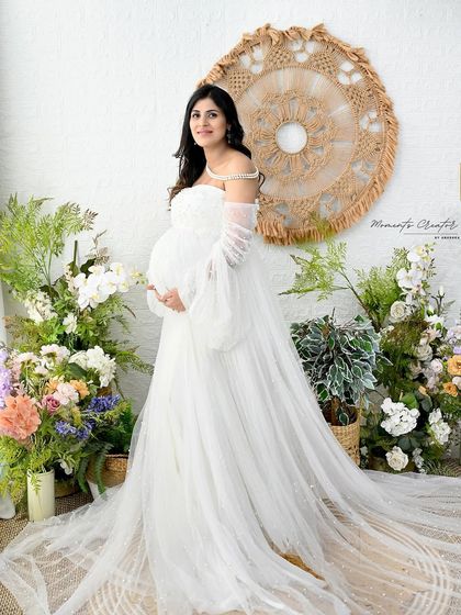 A vision in white. This solo portrait in the floral boho setup showcases the beautiful details of the flowy white gown and the mother's radiant glow.