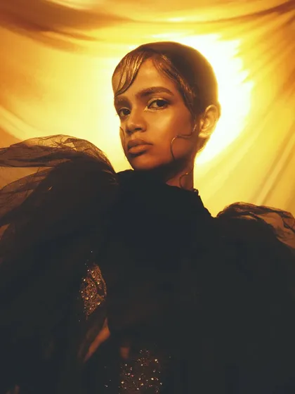 The backlighting in this shot creates a halo effect, making the golden makeup on the model's face and hair truly glow.