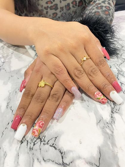 A beautiful floral design perfect for any occasion. This student work features a mix of solid pink, white, and glitter nails, with accent nails showcasing a delicate, hand-painted rose pattern.