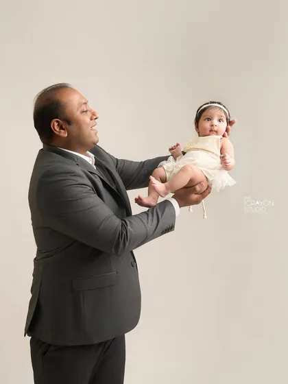 A playful moment where a father lifts his baby, both of them sharing a look of delight. It shows the fun and interactive side of family portraits.