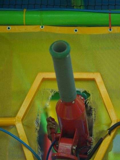 One of the interactive ball cannons, safely enclosed within the netted play structure.