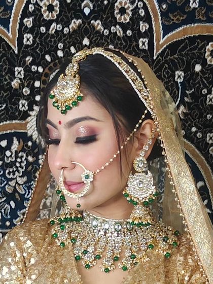A bride in a golden sequin lehenga, wearing a Kundan and green bead set. The matching jhumkas and simple nath complete the look.