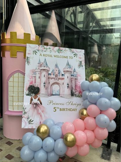The royal welcome sign for Princess Shriya's 5th birthday party. The sign, featuring a watercolor castle illustration, is paired with a pink and blue balloon garland to greet guests in style.