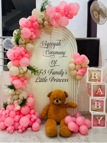 I create beautiful and respectful decorations for religious ceremonies, like this Aqeeqah for a family's 'Little Princess'. The setup includes a personalized arched backdrop, a soft pink and white balloon garland, and classic props like a teddy bear and 'BABY' blocks.