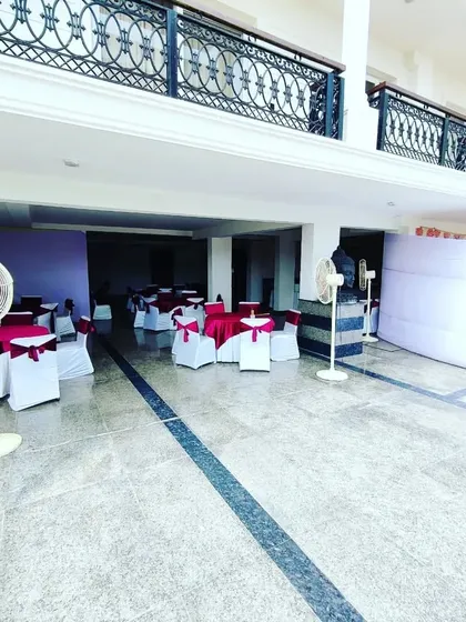 A wider view of an event space we prepared, showing the arrangement of pedestal fans for ventilation, guest seating tables, and a partition for the catering area in a semi-open venue.