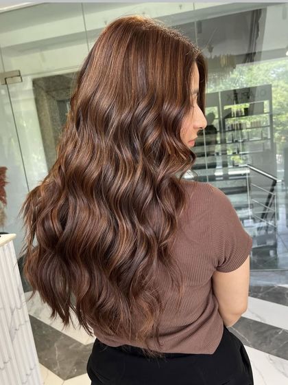 A side profile of our hazelnut hues, showing how the color wraps around the hair to create a full, voluminous look with soft waves.