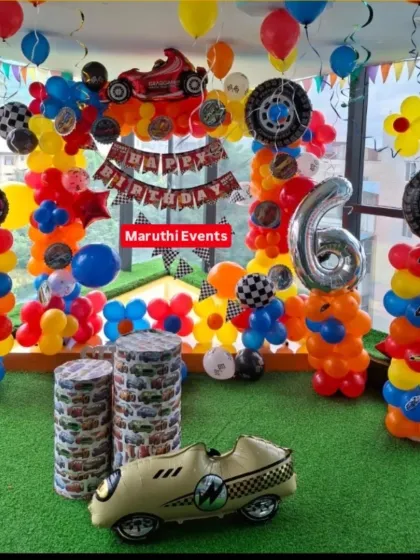 A high-energy racing car theme with bright primary colors. This full-room setup includes balloon columns, a "Happy Birthday" banner with checkered flags, and car-themed props.