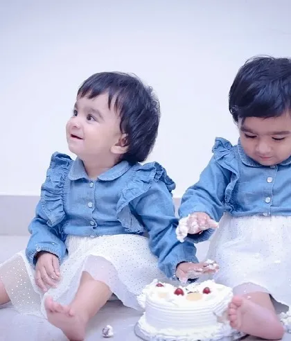 The moment of discovery! One twin starts to dig into the cake, a classic moment in any first birthday cake smash session.