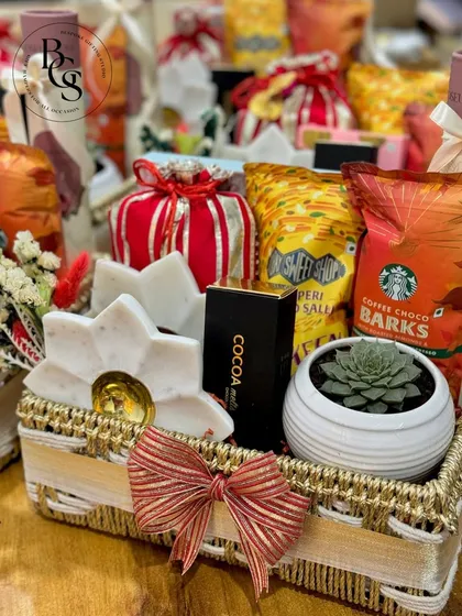 This festive basket, filled with a succulent plant, gourmet snacks, and a marble diya, is a beautiful blend of modern and traditional gifting. The red and gold bow adds a classic festive touch.