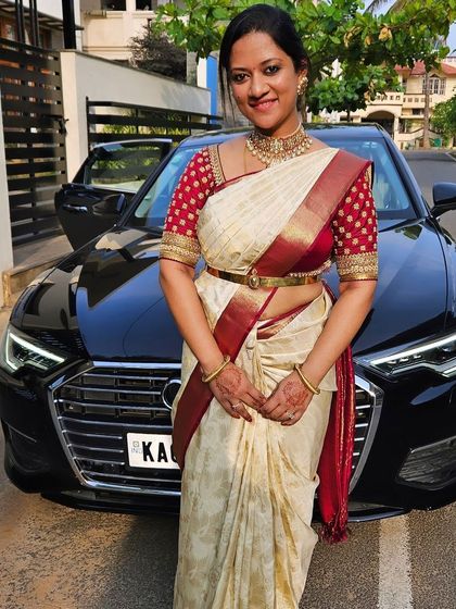 A client looking sharp in an off-white Kanchivaram with a maroon border, paired with a custom red blouse with traditional embroidery.