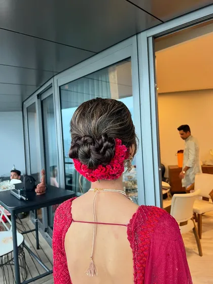 A closer view of the red floral bun, showing the detailed knot work and how the flowers are woven in for a seamless and secure finish.