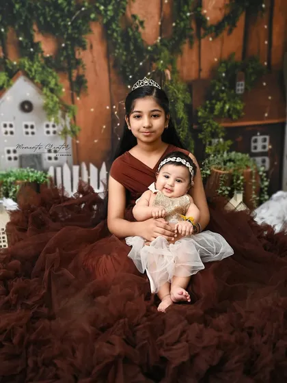 A big sister's love. This heartwarming photo shows a proud older sister holding her two-month-old baby sister, a precious memory of their first photoshoot together.