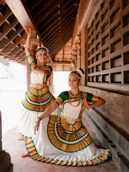 A portrait of two Mohiniyattam dancers in a graceful pose. The symmetry and their coordinated outfits create a visually stunning image.