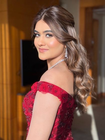 A beautiful reception glam look for this bride in a stunning red off-shoulder gown. The makeup is soft and romantic, with classic waves in her hair.