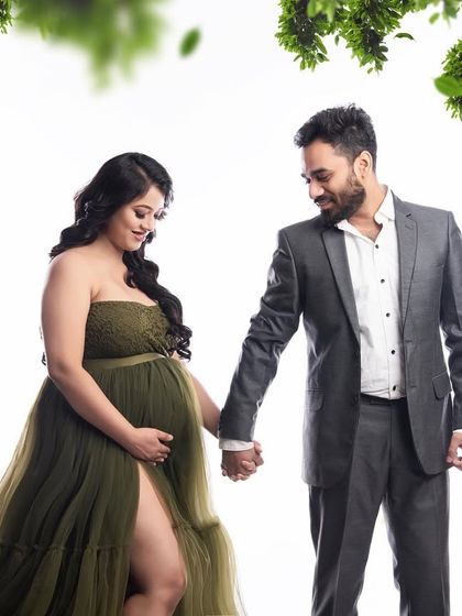 A beautiful couple portrait with a natural, green theme. The mom-to-be is stunning in an olive green gown, and the leafy effects add to the organic, earthy feel of the photo.