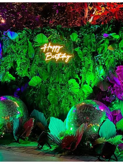 A full view of the 'Happy Birthday' photo booth. I layered neon-lit animal props, disco balls, and a wall of tropical leaves to create a dynamic and textured backdrop that glowed under the party lights.