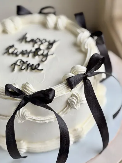 Serving balletcore but with a chic twist. 🎀 This vintage-style cake features delicate buttercream piping and is adorned with elegant black satin bows, perfect for a stylish birthday celebration.