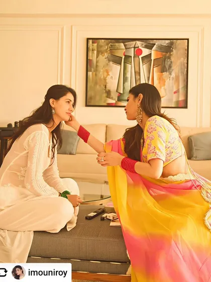 A candid moment between Mouni Roy and Disha Patani, with Jagannath Paul's figurative art adding emotional depth to their living space.