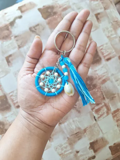 A vibrant blue shell dreamcatcher keychain, reminiscent of clear ocean waters and sunny skies.