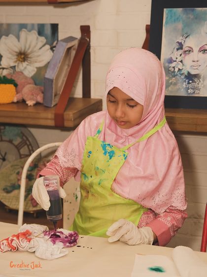 This young girl in a hijab is carefully applying purple dye to her fabric. My workshops are inclusive and welcoming to children from all backgrounds.