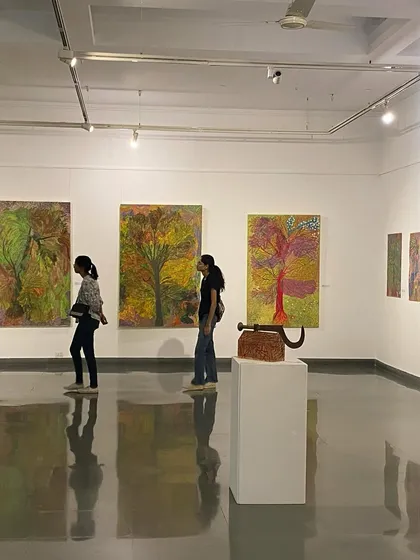 Visitors walking past the vibrant, large-scale paintings.