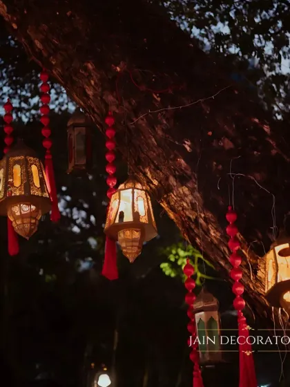 Details that create a magical atmosphere. I used hanging lanterns and red tassels to adorn the trees, adding a warm, ambient glow to the outdoor sangeet space.