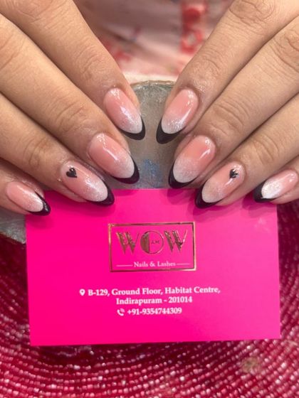 A creative combination of styles, this look features a soft ombré base with a sharp black French tip and delicate heart details.