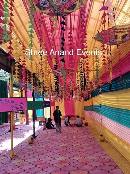 The entrance to a Mehndi ceremony, decorated with colorful drapes, hanging tassels, and traditional Rajasthani umbrellas.