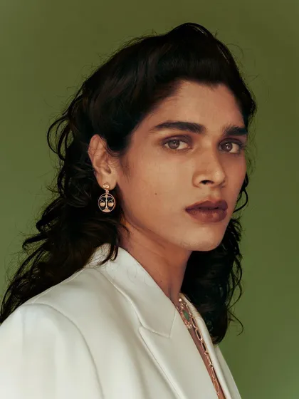 A portrait from a new campaign for Amama Jewels against a solid green backdrop. The clean, colorful setting makes the model and the intricate zodiac-themed earrings the central focus.