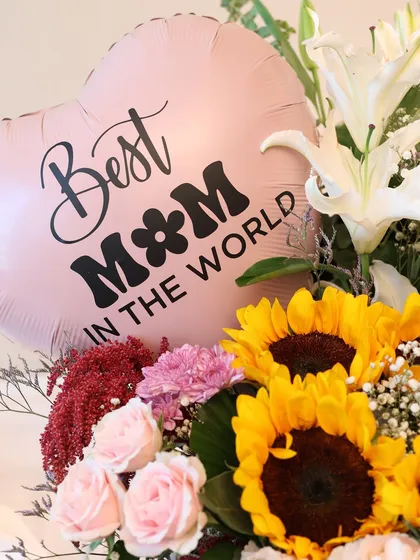 A close-up of the "Best Mom in the World" balloon, surrounded by sunflowers and lilies. This detail shot shows the vibrant colors and fresh quality of the flowers I use.