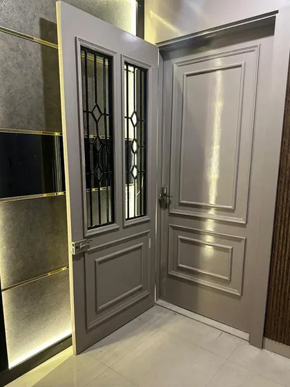 A beautifully crafted main door featuring a classic panelled design with modern glass and ironwork inserts. The sophisticated grey finish and elegant hardware make for a grand and welcoming entrance.