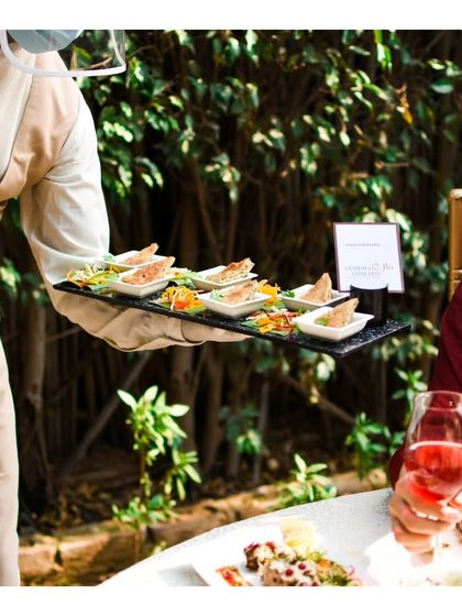 A server presents appetizers to a guest at an outdoor event. This image captures the seamless flow of our passed hors d'oeuvres service.