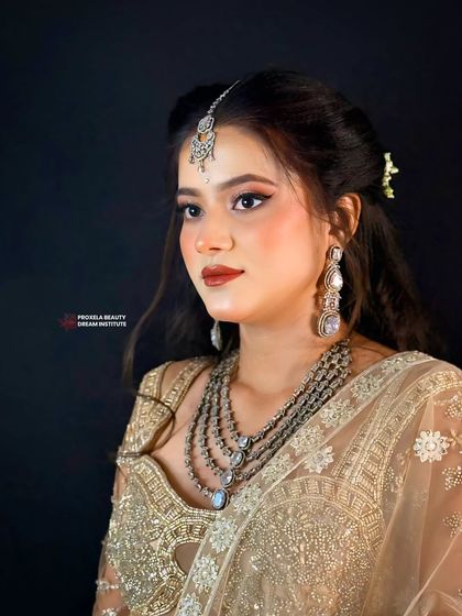 A soft and glowing look for a daytime event or festival. The hair is styled with gentle waves and a simple half updo, letting the intricate gold outfit and layered necklace shine.