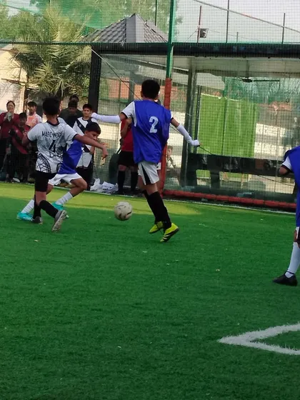 A young player skillfully dribbling past defenders, showcasing the technical ability we instill in our trainees.