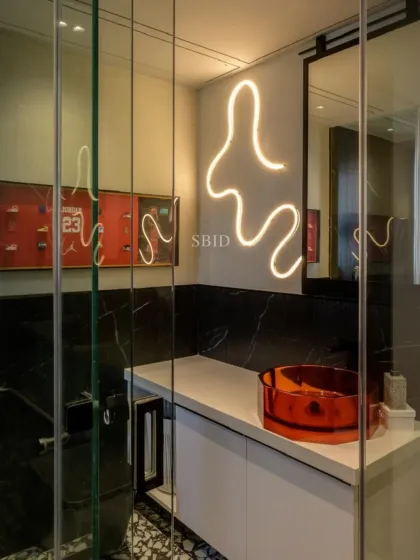 The son's bathroom is edgy and cool, with black marble, a vibrant orange glass basin, and a custom neon light scribble on the wall. The framed Michael Jordan shoe collection adds a personal touch.