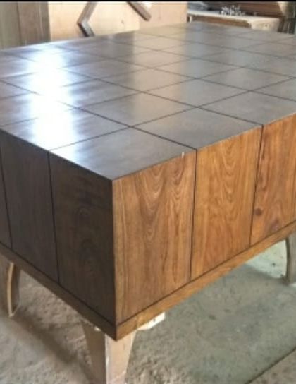 The same custom center table after polishing. The finish brings out the deep, warm tones of the teak wood, highlighting the grid pattern on the top surface.